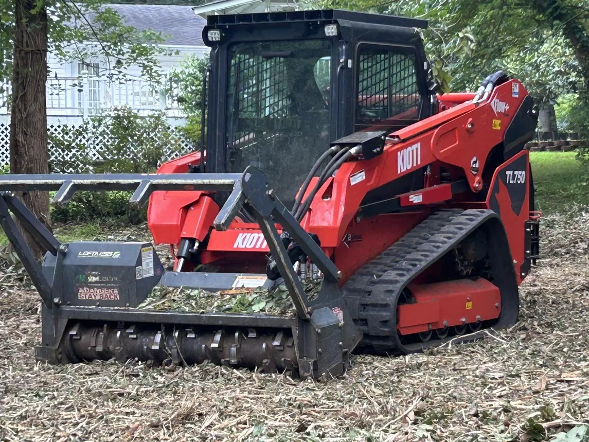 Red track loader with a forestry mulching head on mulched ground
