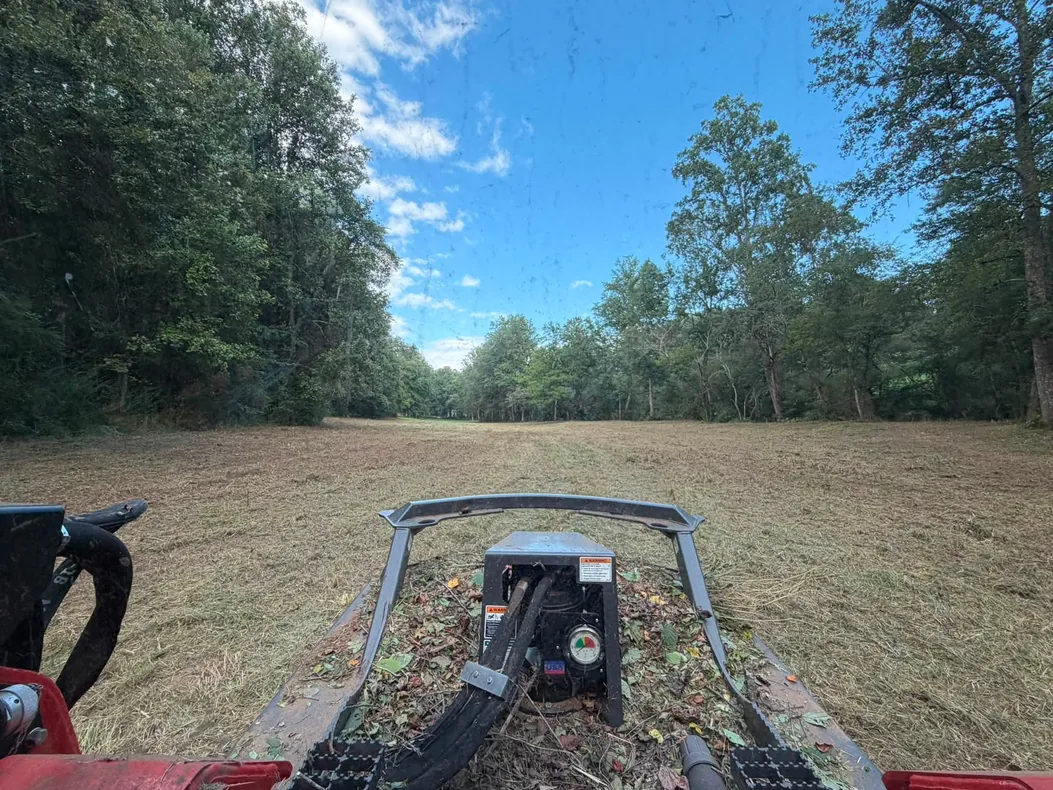 Freshly cut field seen from the track loader with the brush cutter in front, bush hogging