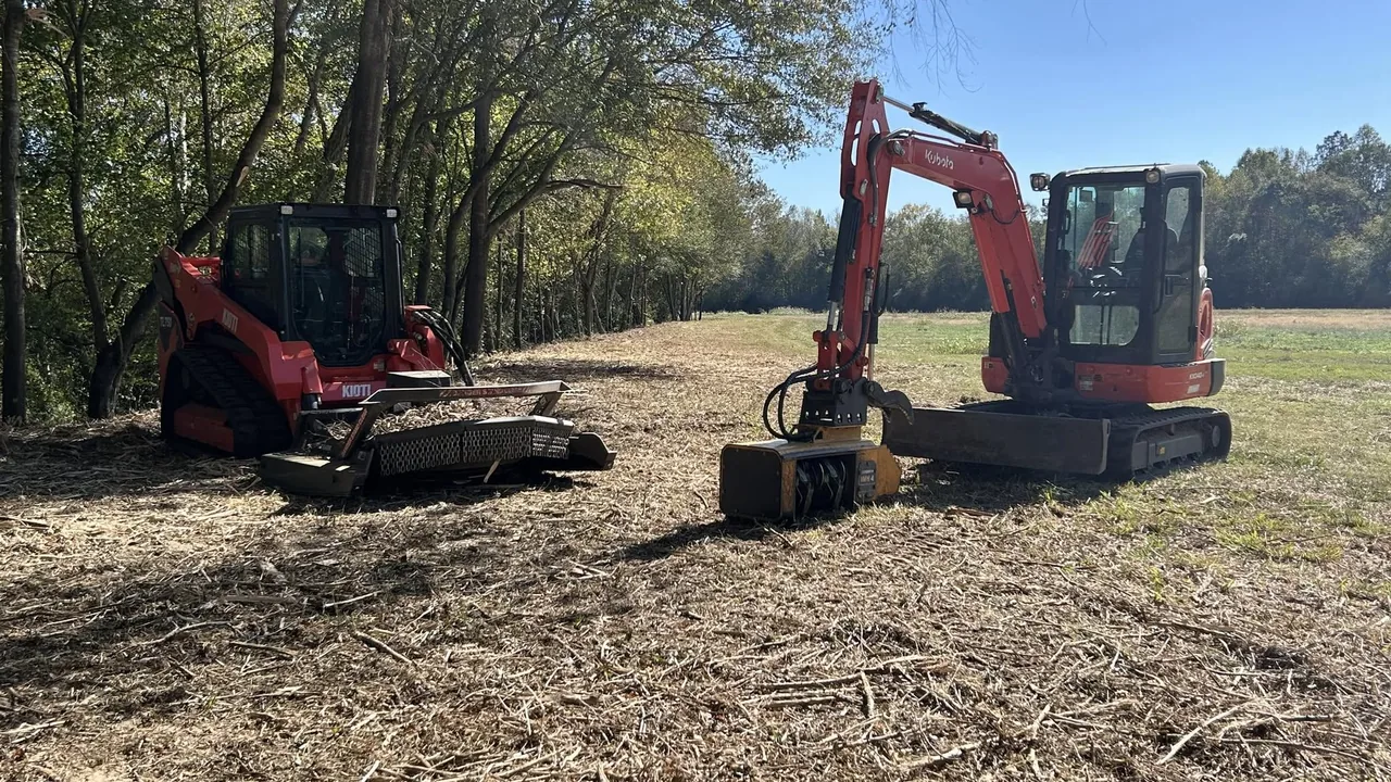 Red track loader with a brush cutter and a red mini excavator with a mulching head on a freshly mulched field, land clearing