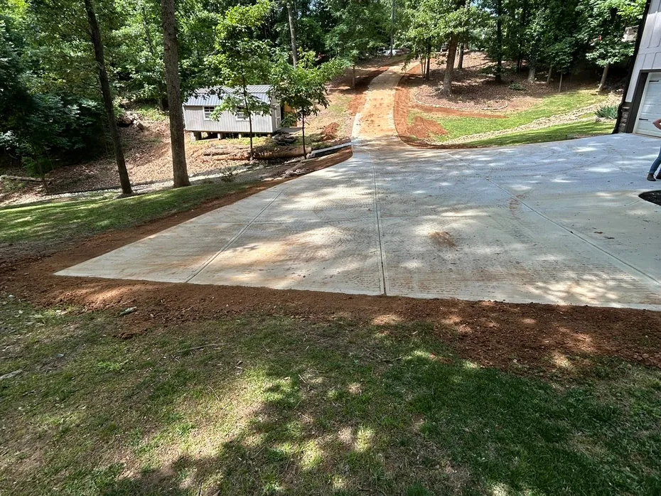 Fill dirt graded up to the edge of a new concrete driveway, land grading