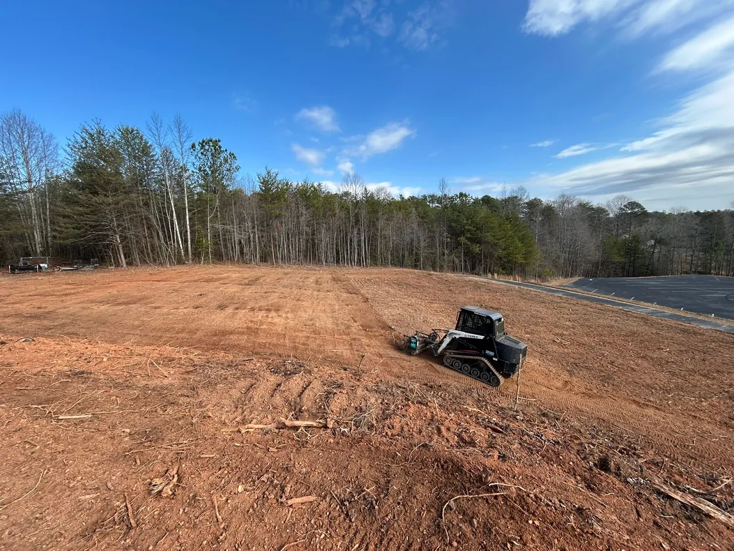 Graded red clay pad with a track loader at work, land grading